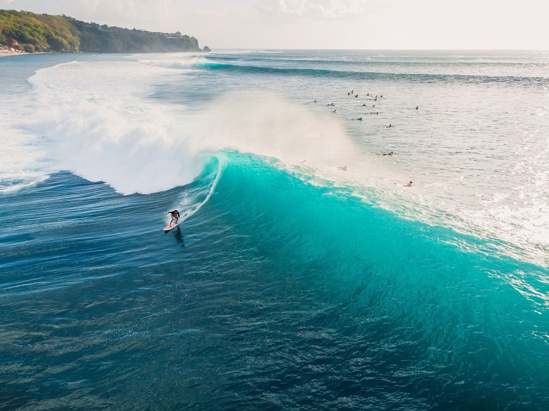 Surfař na velké tyrkysové vlně u pobřeží Bali
